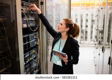 Technician holding digital tablet while examining server in server room - Powered by Shutterstock