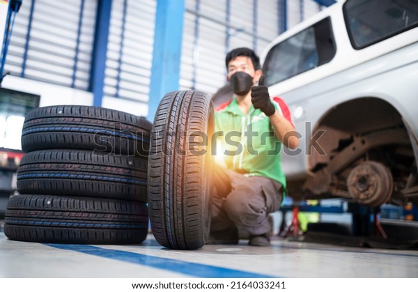 Technician holding a tire at a tire\
changing garage Set of four tires at a car service\
center