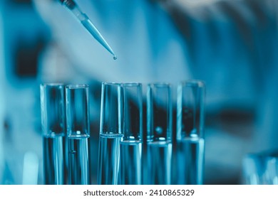 Technician holding tube test in the research laboratory, chemist's hand taking a solution sample tube from a rack with machines of analysis in the lab, Dripping liquid from pipette into tube. - Powered by Shutterstock