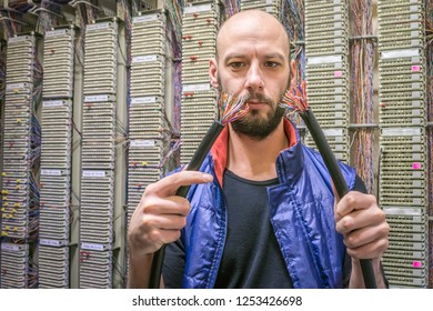 A Technician Holds In His Hands The Two Ends Of A Torn Telephone Cable. An Engineer Will Connect A Damaged Internet Backbone. The Worker Restores The Connection In The Data Center Server Room.