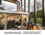 A technician inspects and repairs the inner workings of a hot tub in a backyard setting during cloudy weather.