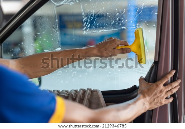 Technician Installing car window tint. Car\
window tinting series. Car window tinting specialist install car\
film windscreen.