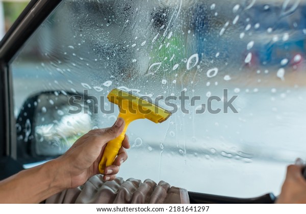 Technician Installing car window tint. Car\
window tinting series. Car window tinting specialist install car\
film windscreen.