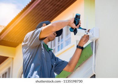 Technician is installing CCTV camera system at house by Cordless battery drill