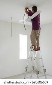 Technician In Installing Ceiling Fan In Newly Built House