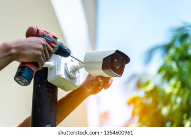 Technician installing IP wireless CCTV camera by screwed for home security system and installed white plastic boxes for safe from water and rain - Shutterstock ID 1354600961
