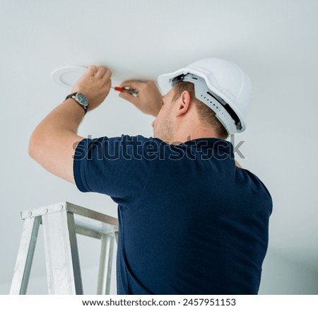 technician is installing an LED spotlight in the ceiling.