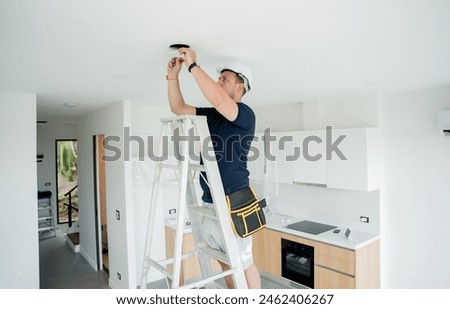 technician is installing an LED spotlight in the ceiling.