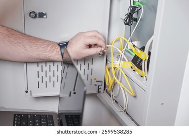 technician installing network cable in server cabinet while configuring internet connection for IT infrastructure