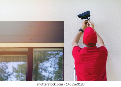 technician installing outdoor security surveillance camera on house exterior wall