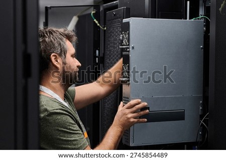 IT technician installing server hardware in a data center during routine maintenance and system upgrade