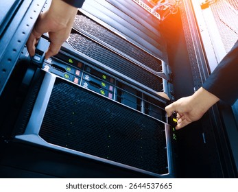 A technician is installing a server into a data center rack, showcasing the intricate technology and hardware necessary for modern computing environments.