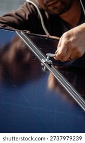 Technician installing solar panel mount on a residential house roof close up.