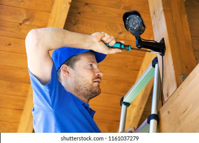technician installing surveillance camera in the house carport