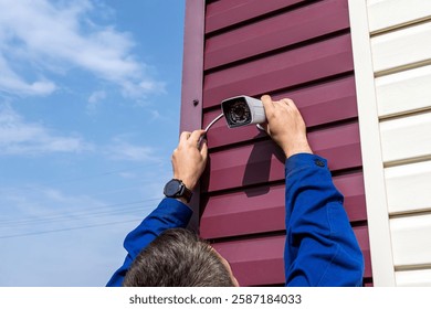 Technician installing wireless CCTV camera at house for security. A video surveillance camera in the hands of a technician. Installation of outdoor video surveillance in close-up.