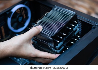 A technician installs an aluminum air-cooled heatsink on a desktop PC CPU. Air Cooler CPU. PC assembly. Technician's hands hold new CPU heatsink. Computer tech background