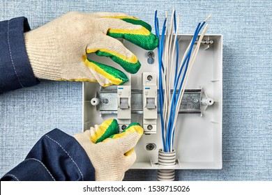 Technician Installs A Home Fusebox Or Electrical Consumer Unit Wiring Panel. Electrician Install Circuit Breakers On A DIN Rail When Mounting A Distribution Box In A House. Electric Installation Work.