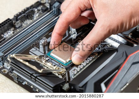 A technician installs an Intel i7-9700K CPU in 1151 socket on a Gigabyte motherboard. PC assembly and upgrade concept