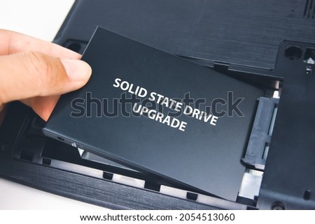 A technician installs a Solid State Drive (SSD) in a laptop computer
