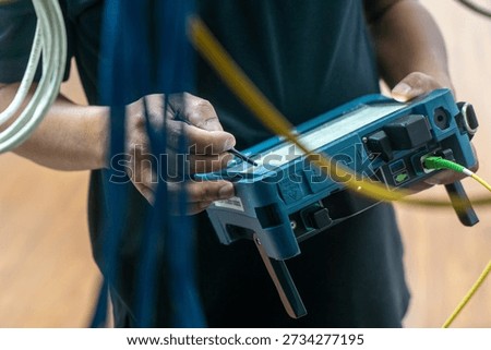 A technician interacts with advanced network test equipment, conducting diagnostics and measurements amidst a backdrop of cables and technology.