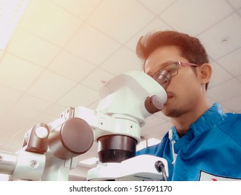 Technician looking equipment in microscope for repair - Powered by Shutterstock