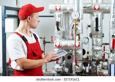 Technician maintenance repairman engineer inspecting heating system in boiler room
