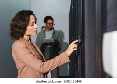 technician making diagnostics of server in data center near blurred african american colleague with digital tablet
