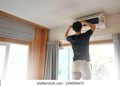 Technician Man Repairing ,cleaning And Maintenance Air Conditioner On The Wall In Bedroom.On Site Home Service,Business ,Industrial Concept.