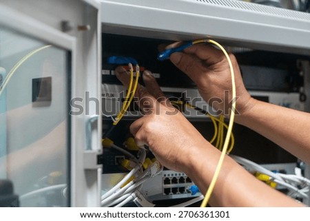 A technician manages network cables in a computer room, ensuring proper installation and maintenance for optimal performance of IT infrastructure.
