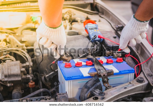 Technician measure voltage of battery in the car by\
multimeter. Selective\
focus