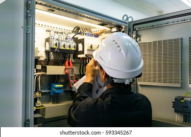 Technician is measuring voltage or current by voltmeter in control panel of power plant, selective focus on safety helmet - Shutterstock ID 593345267