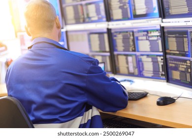 Technician monitoring data on multiple screens in a control room.