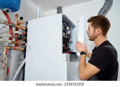 Technician open control panel with internal wiring to inspecting heat pump unit. Specialist servicing heating and cooling system. Concept of HVAC maintenance, home heating system and energy efficiency