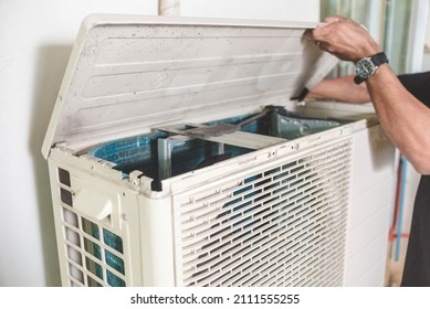 A Technician Opens Up The Top Hatch Of The Outdoor Compressor Unit Of A Split Type Air Conditioner. Repair Or Maintenance Work.