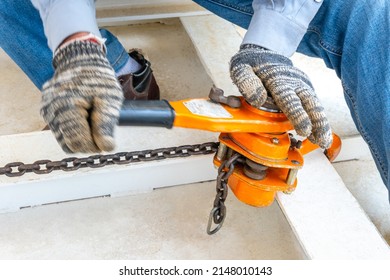 Technician Is Operating Lever Tight Chain Hoist In Factory.