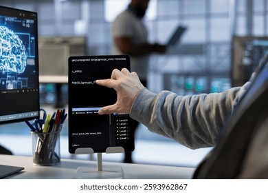 Technician optimizing data center workspace with tablet for maximum efficiency and uptime. Programmer in server hub maintaining optimal network performance, performing backups using device, close up