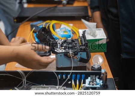A technician performs detailed work on an electronic device with circuit boards and microchips, using tools in a professional workspace dedicated to electronics repair.