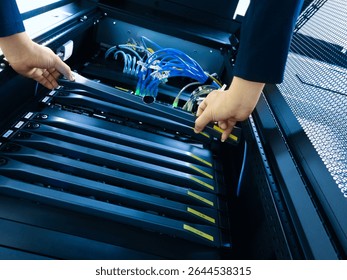 A technician performs maintenance on server equipment in a data center. The image shows hands working with organized cables and server hardware.