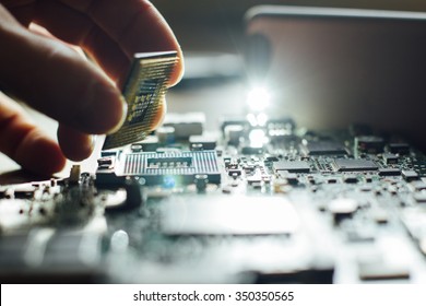 Technician plug in CPU microprocessor to motherboard socket. Workshop background - Shutterstock ID 350350565