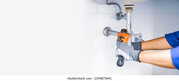 Technician Plumber Using A Wrench To Repair A Water Pipe Under The Sink. Concept Of Maintenance, Fix Water Plumbing Leaks, Replace The Kitchen Sink Drain, Cleaning Clogged Pipes Is Dirty Or Rusty.