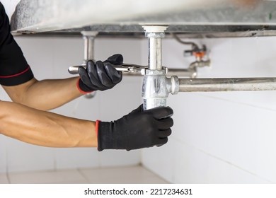 Technician Plumber Using A Wrench To Repair A Water Pipe Under The Sink. Concept Of Maintenance, Fix Water Plumbing Leaks, Replace The Kitchen Sink Drain, Cleaning Clogged Pipes Is Dirty Or Rusty.