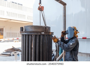 Technician in a protective equipment is working with a welding torch in workshop. - Powered by Shutterstock