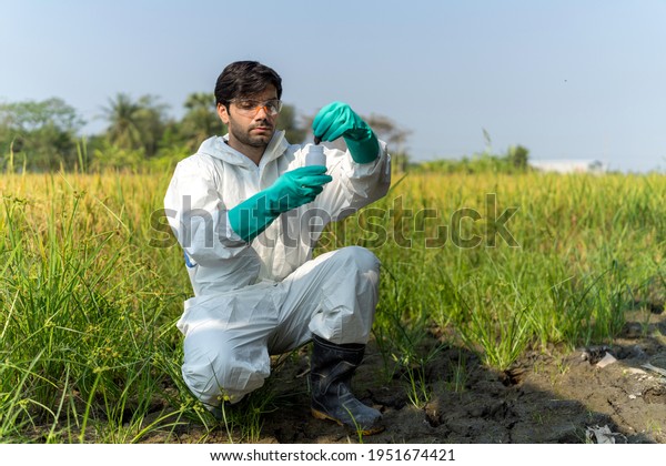 A technician in protective suit collecting\
samples of soil potentially contaminated by toxic material. soil\
quality monitoring concept.