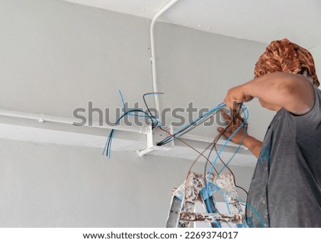 Technician pull wire from conduit in building site.