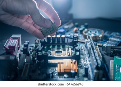 The technician is putting the CPU on the socket of the computer motherboard. - Shutterstock ID 647656945