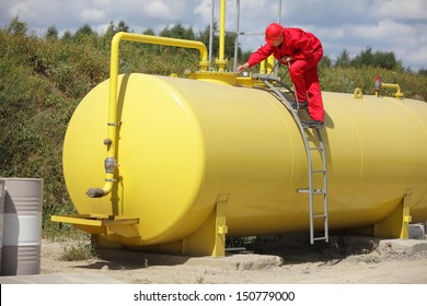 technician in red uniform working on large fuel tank  - Powered by Shutterstock