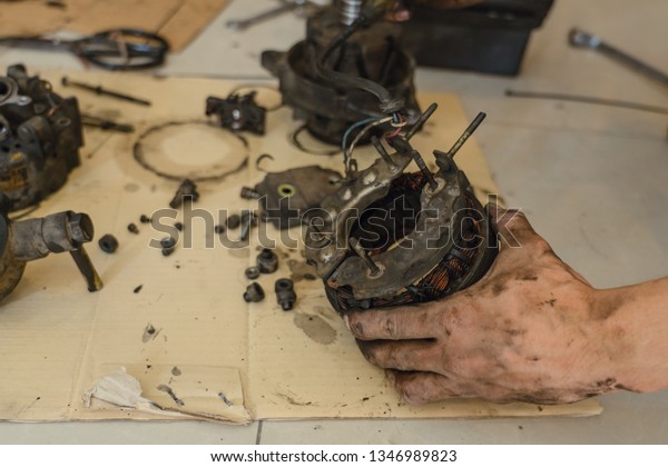 Technician repair old automotive power generator\
alternator for car in\
garage.