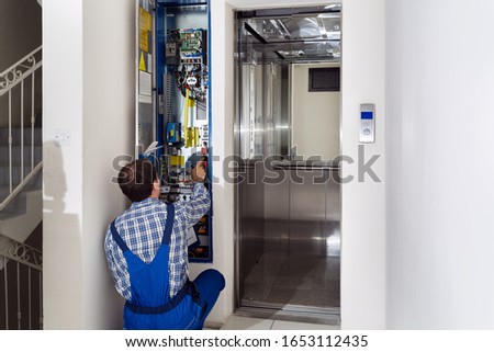 Technician Repairing Control Panel Of Broken Elevator