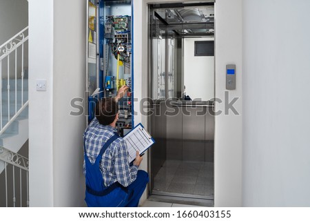 Technician Repairing Control Panel Of Broken Elevator