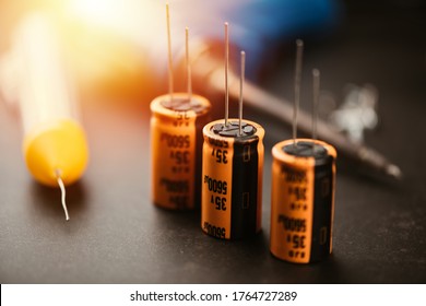 Technician repairing the electronic device. Reparing the audio amplifier. Close up at the orange capacitor.
